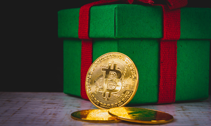 Bitcoin coin in front of a Christmas gift