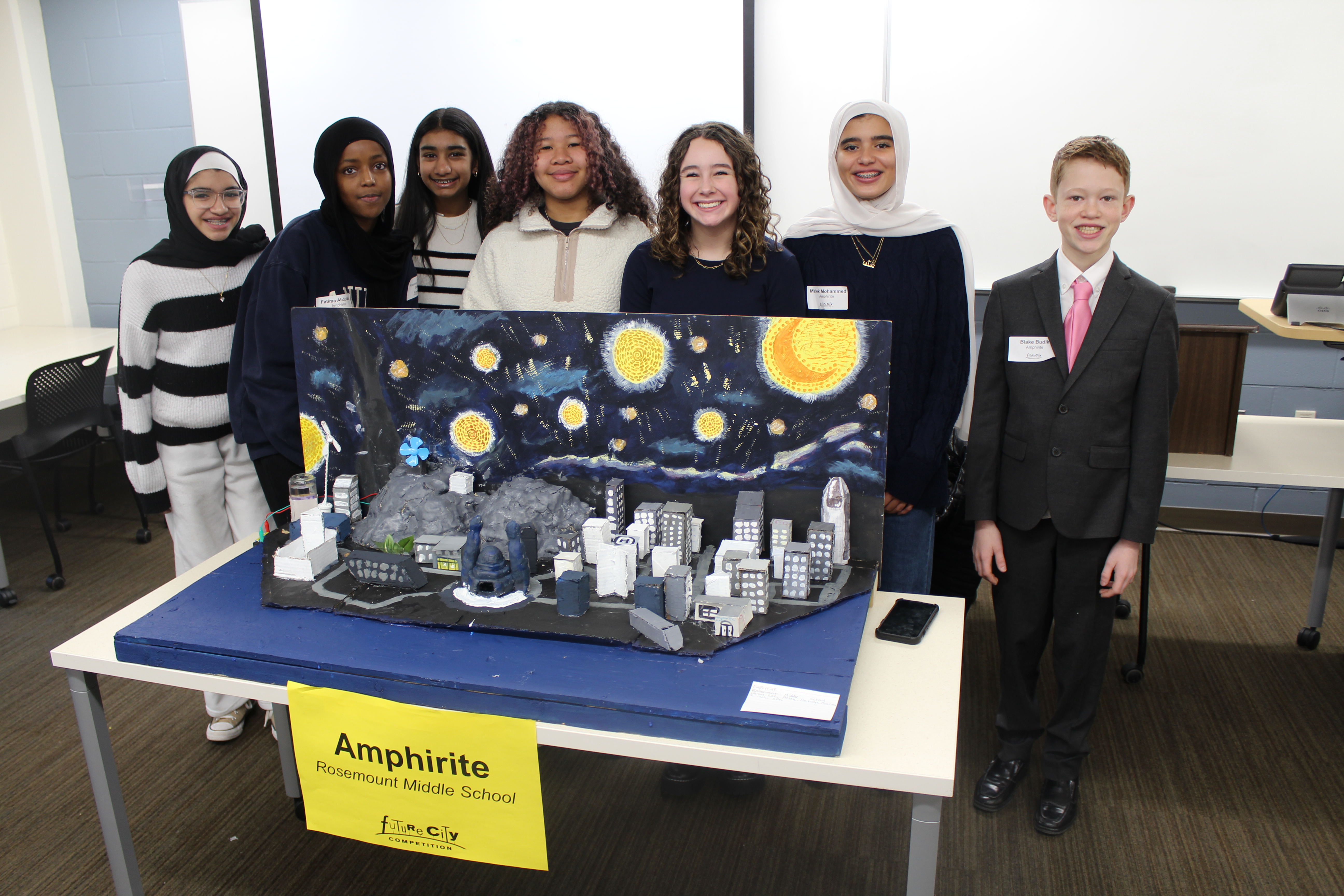 Seven students stand behind their future city model.