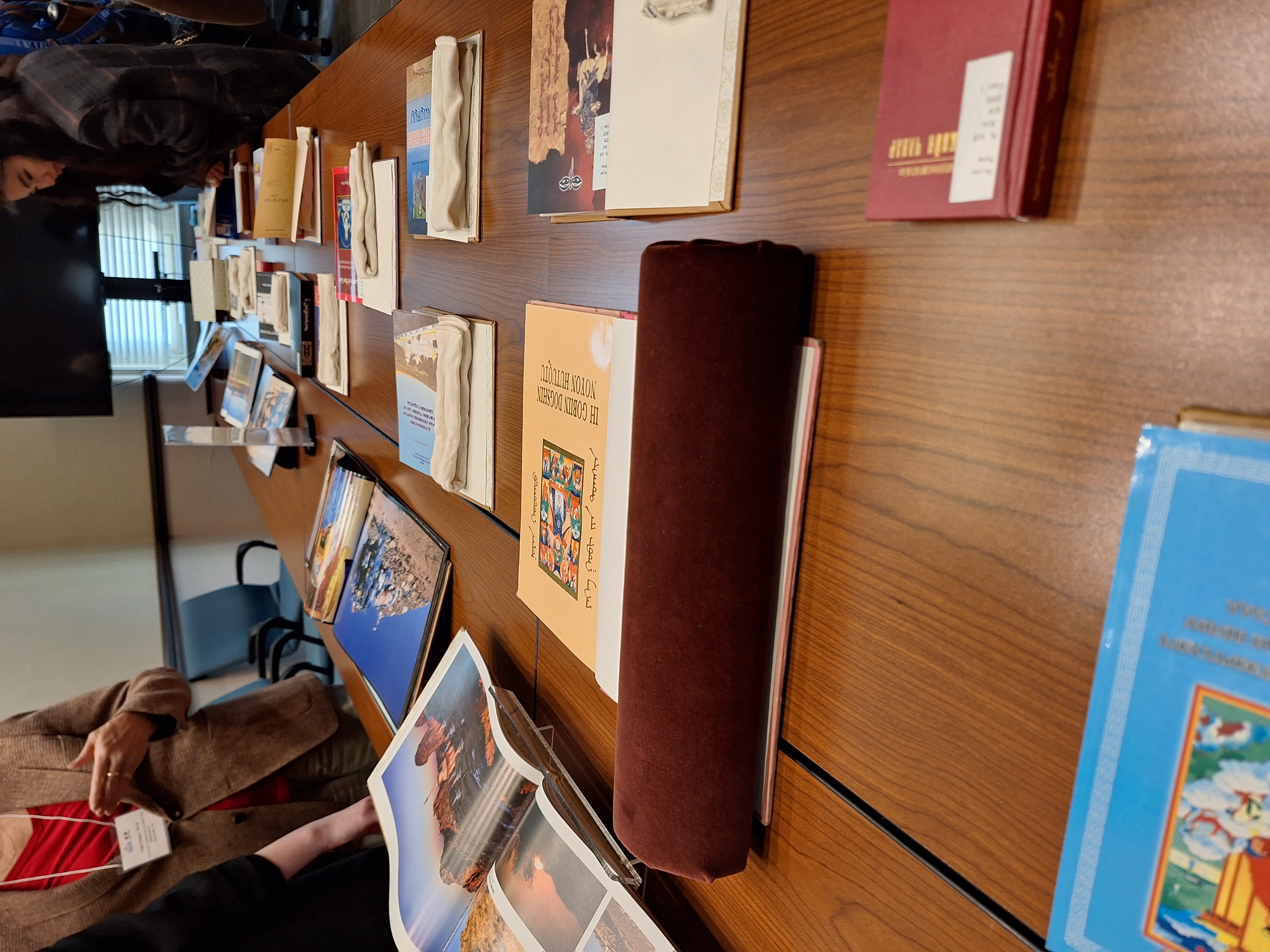 A table with dozens of open books displaying images and text related to Mongolian Studies 