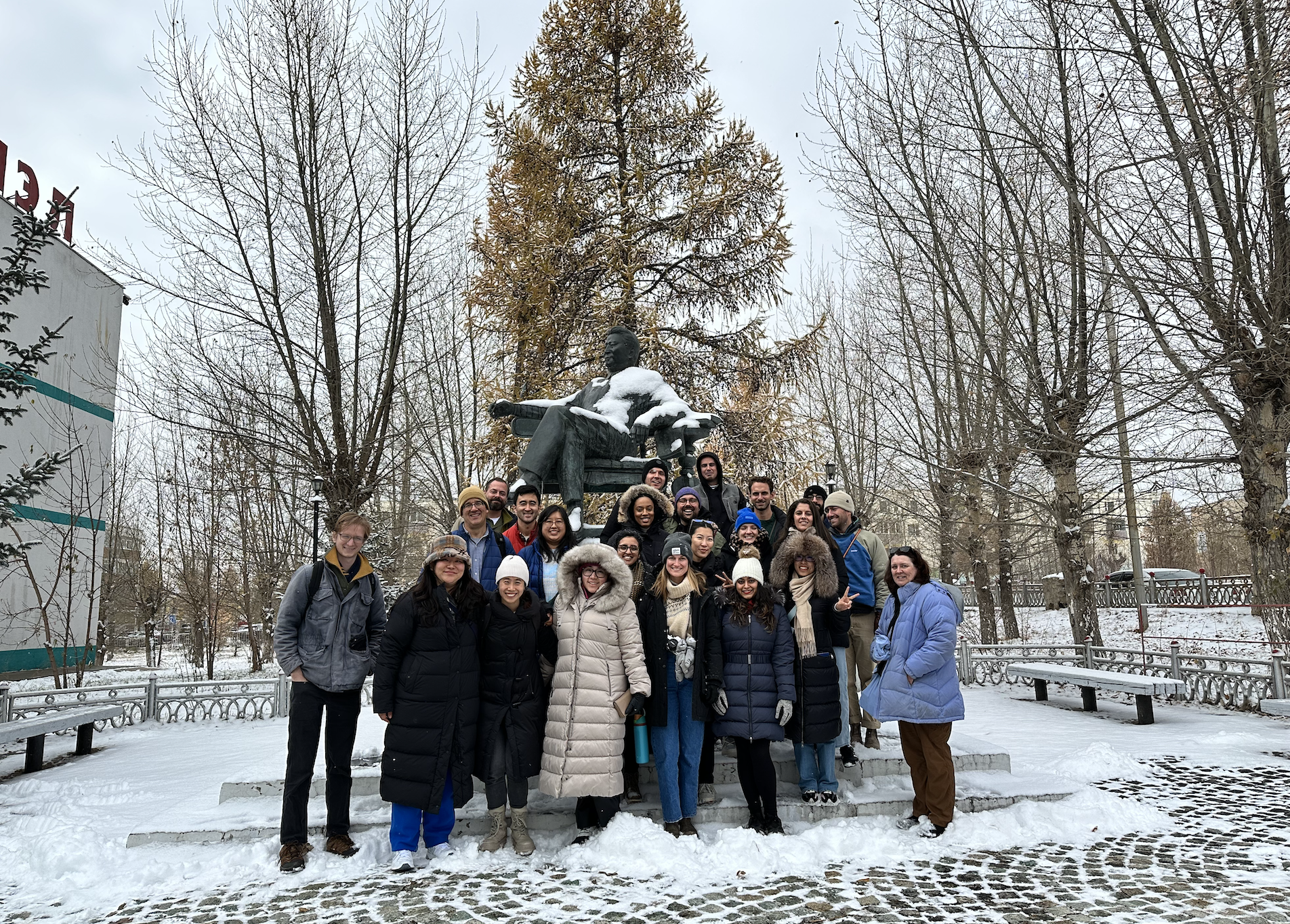 A group of students standing in the snow in front of a statue