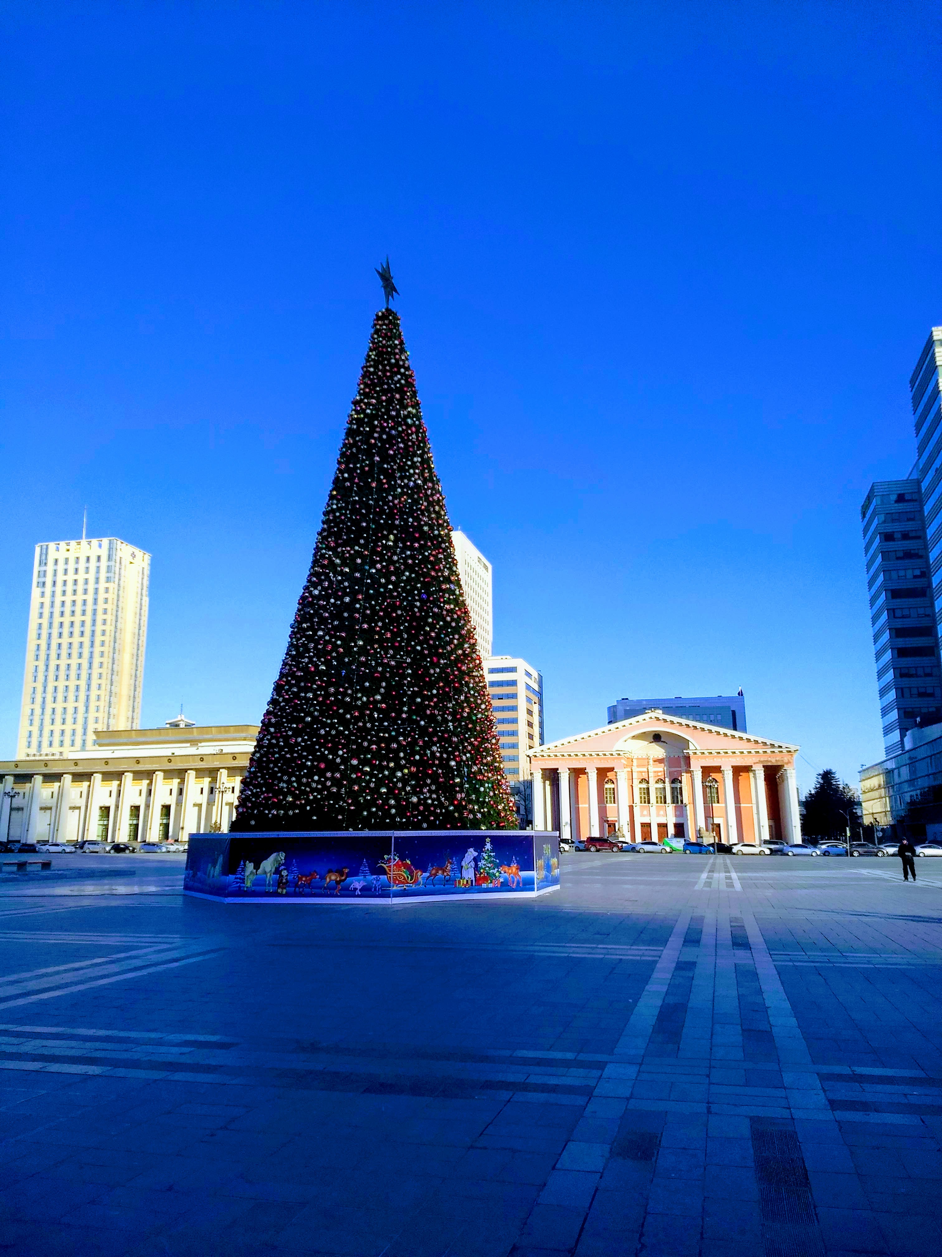 A photo of a large decorated Christmas/New Year's tree in the middle of Suhkbaatar Square, Ulaanbaatar.