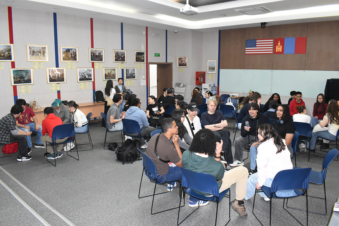 Young people sitting in small groups speaking with one another in a community room.