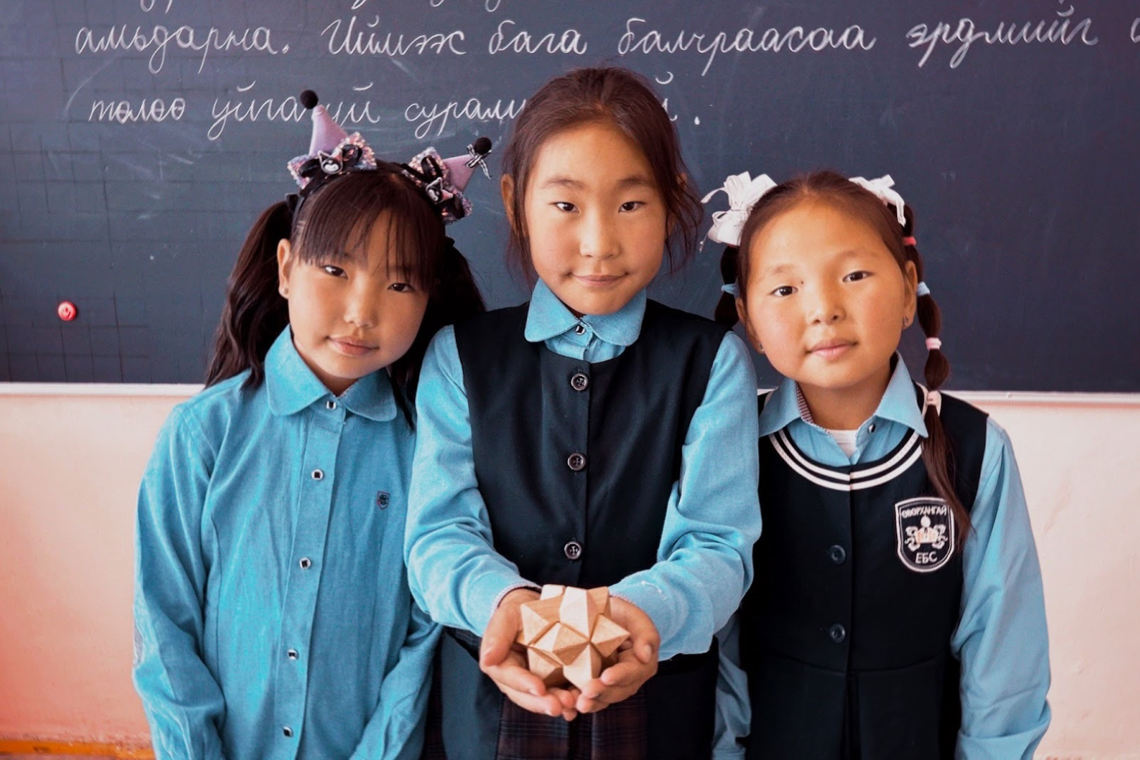 A group of people sitting in rows in an auditorium looking at the camera and smiling