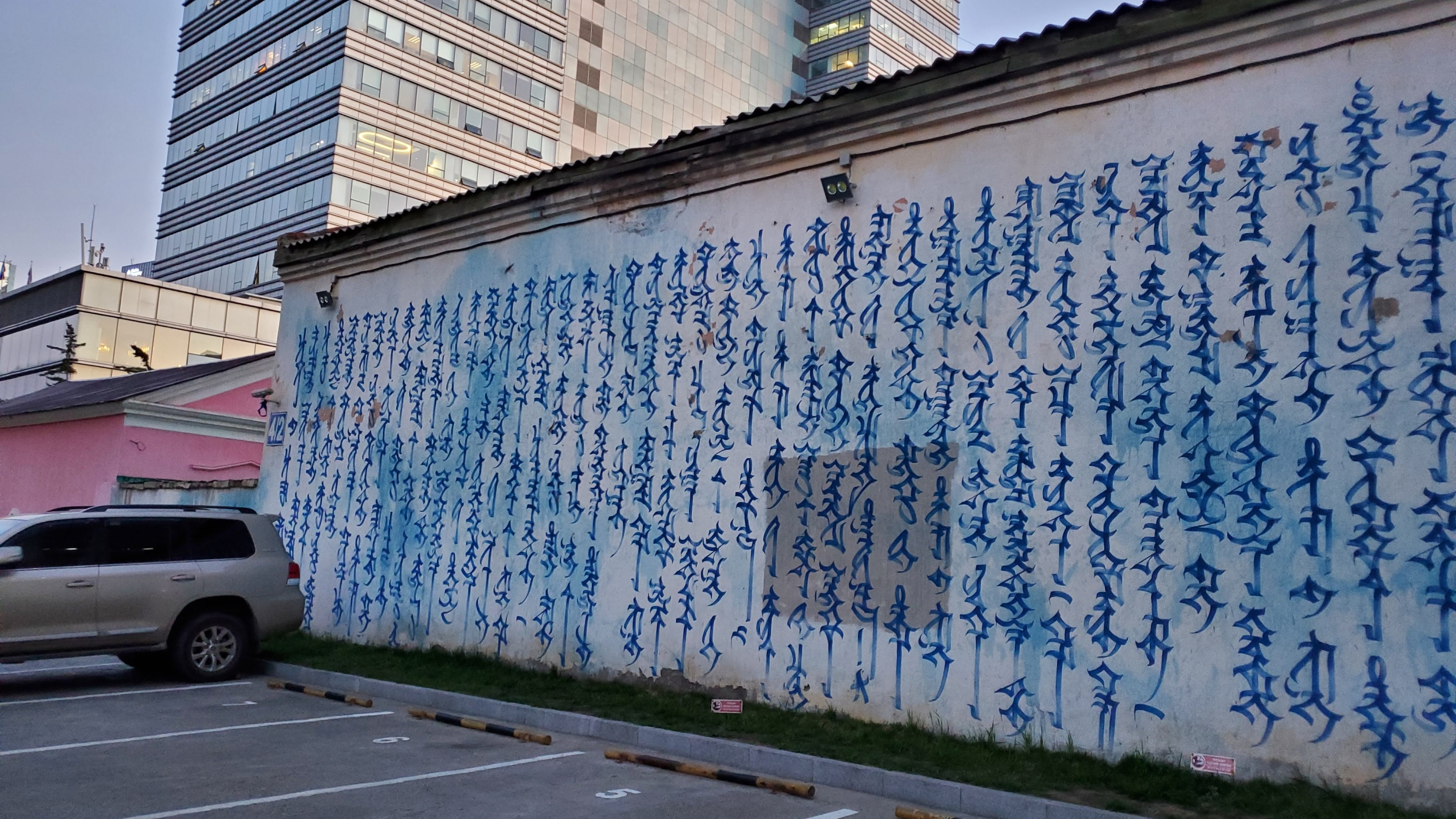 A picture of a white wall with graffiti in traditional Mongolian script.