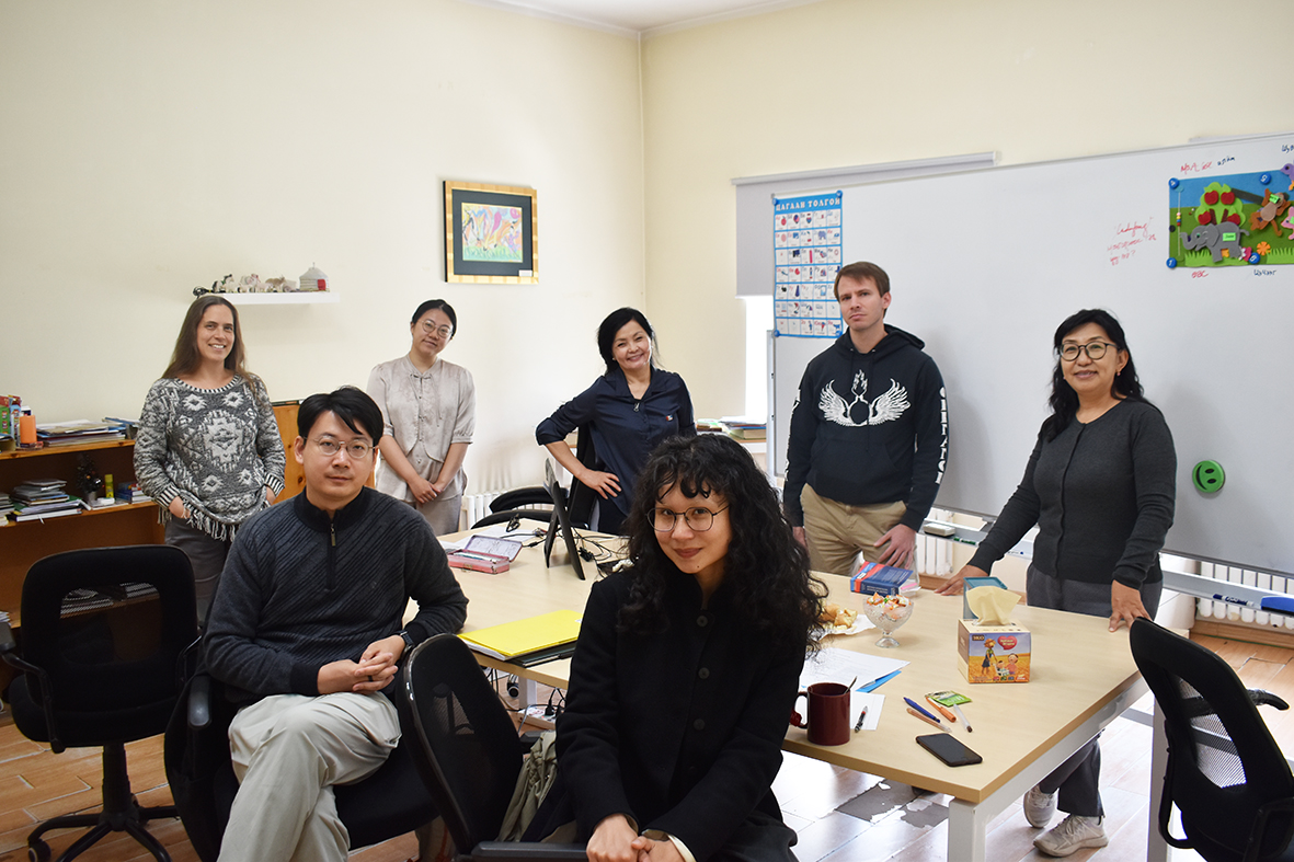 Seven people stand in a classroom and pose for the camera.