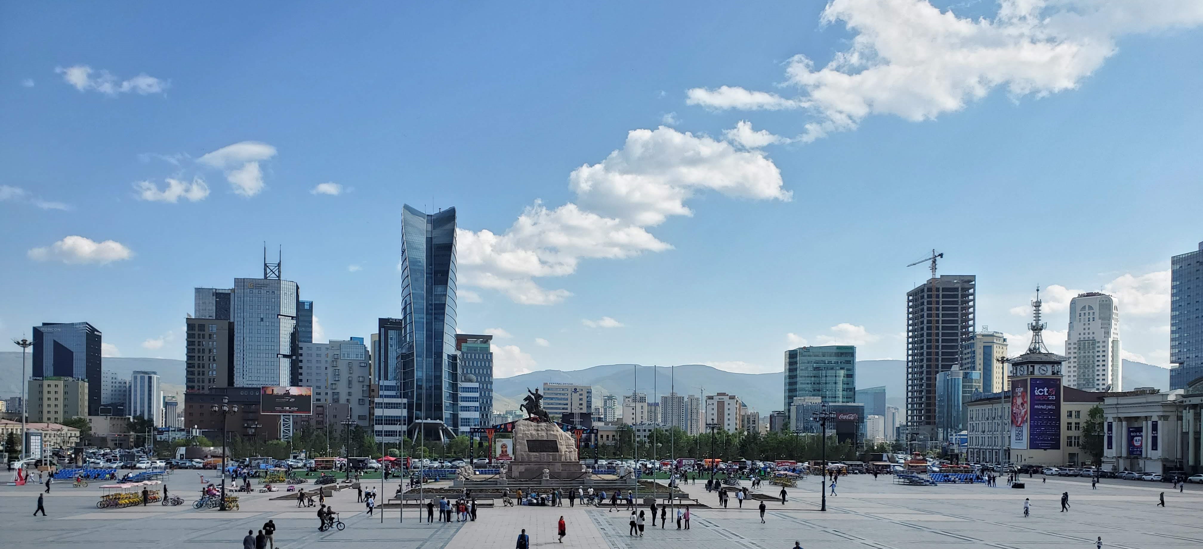 An image of the Ulaanbaatar skyline with many tall buildings and a wide public plaza in the foreground
