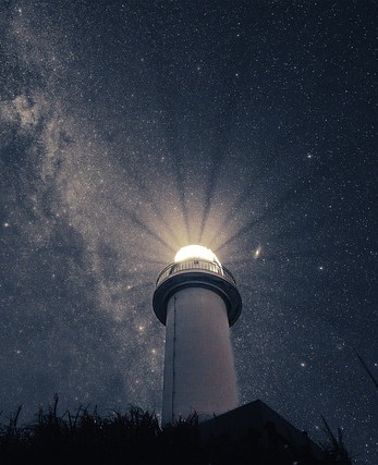 Picture of a lighthouse shining light into the universe