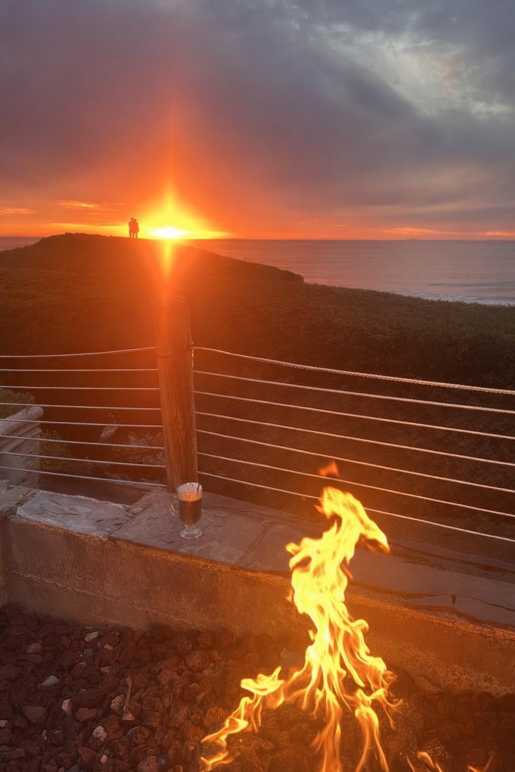 cozy firepit view of couple on hilltop watching beautiful winter sunset