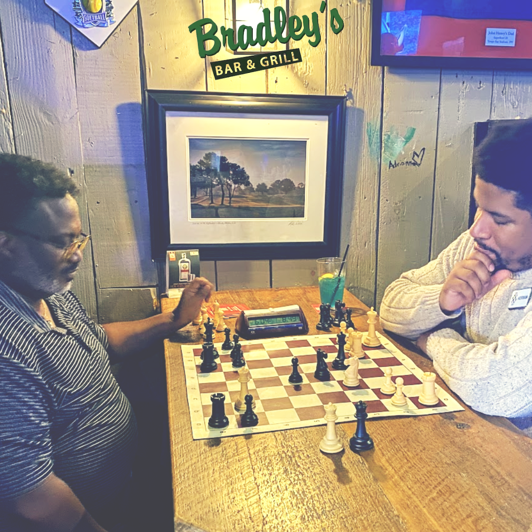 two men playing chess in a bar