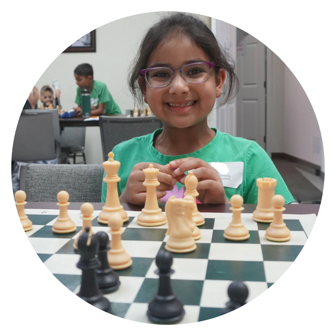 Girl in green shirt smiling over a chess board.