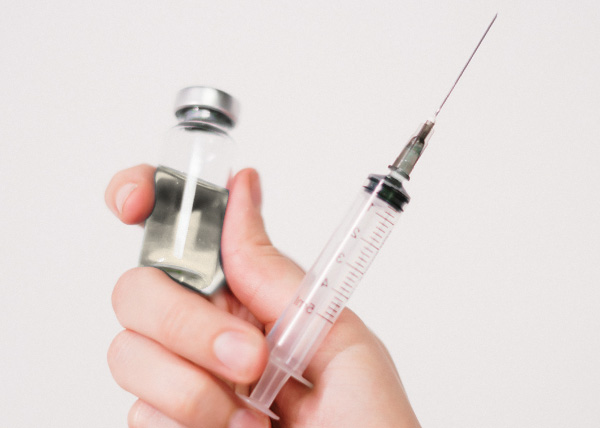 Photo of a hand holding a syringe and a pharmaceutical product