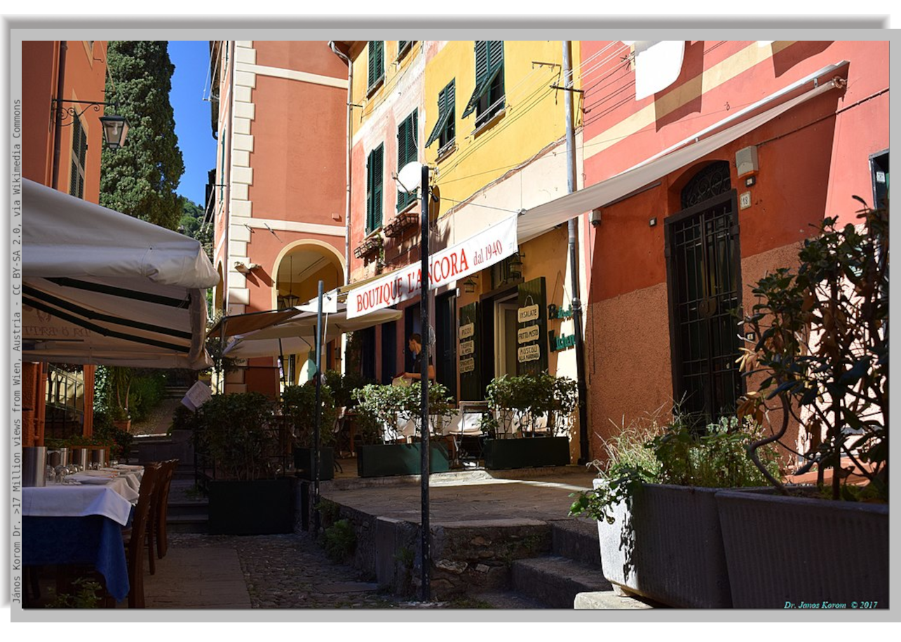 Internal alley in Portofino village among coloured houses, with open air section of a restaurant