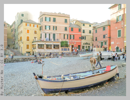 The beach of Boccadasse with colourful houses all around and a gozzo (typical ligurian little boat) pulled up onto the shore