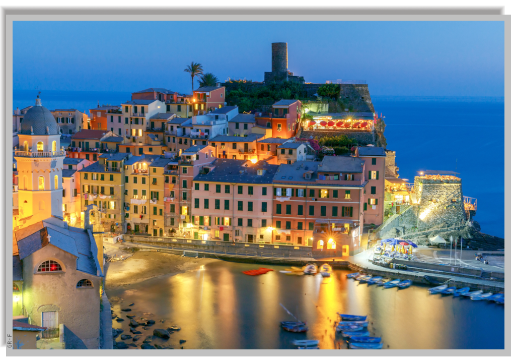 Vernazza village and its cove illuminated at night - view from a nearby hill