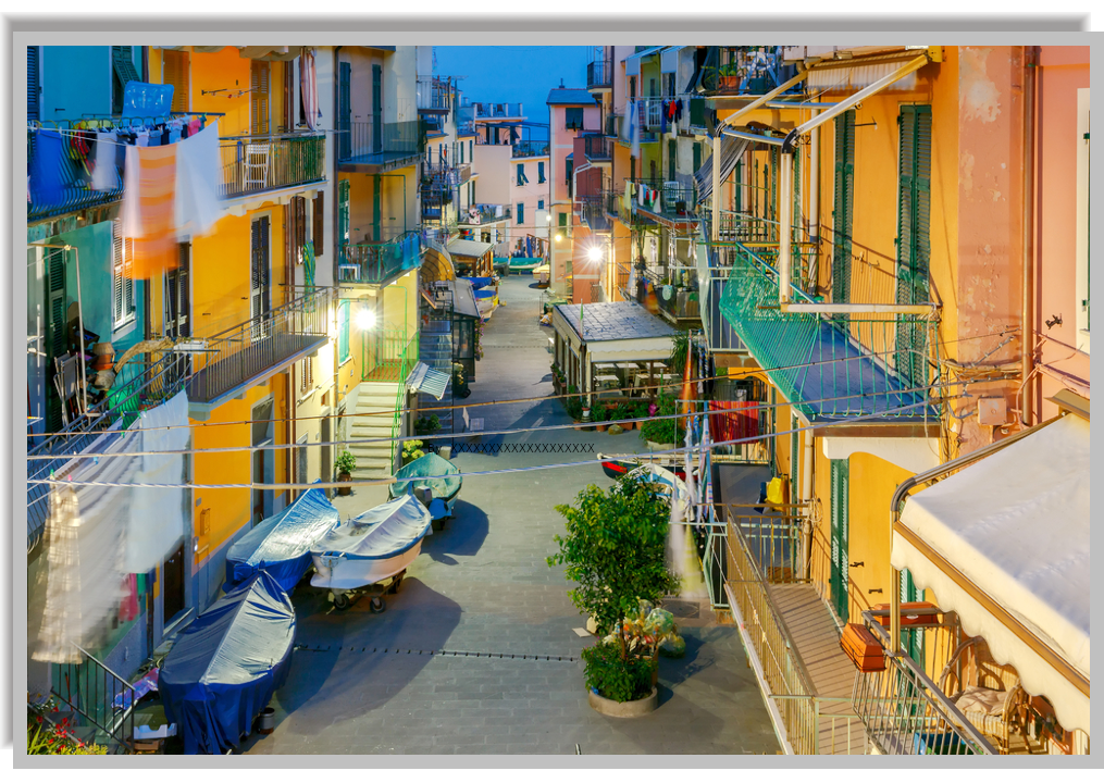 Pedestrian street in Manarola, lined with colorful houses, with boats pulled up and parked along the way