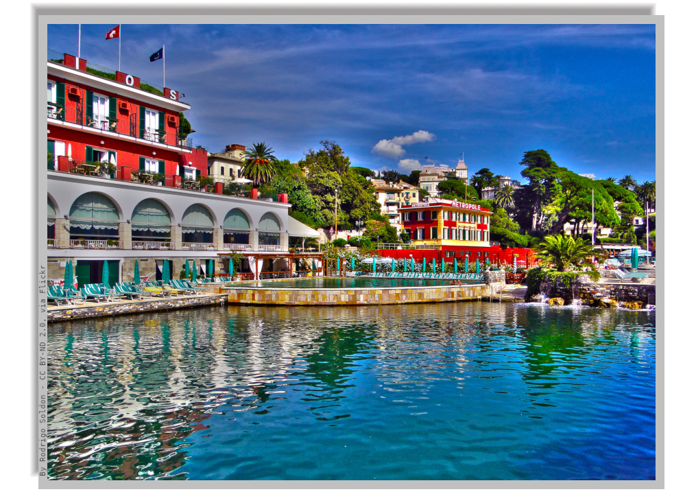 Hotels on the seashore with pool by the calm sea waters, with deck chairs all around