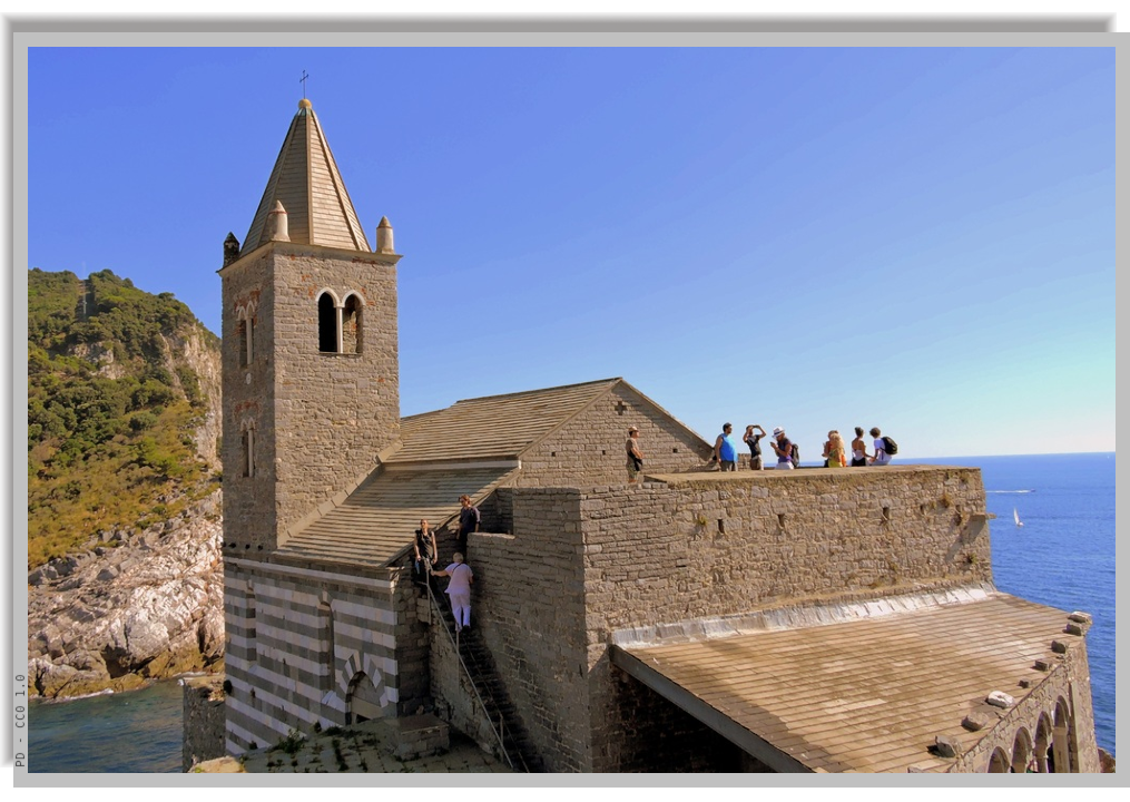 Close view of Saint Peter church, with some tourists admiring the sea from its outdoors upper terrace