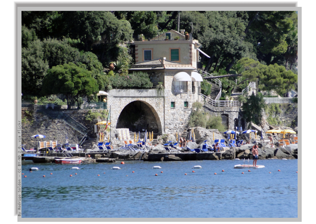 Coastline with deck chairs on piers and a stone building surrounded by green nature