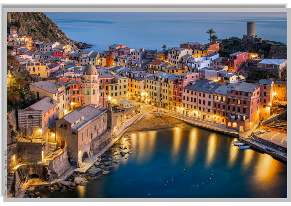 Vernazza village in the evening, with lights reflected on the calm sea waters of the cove