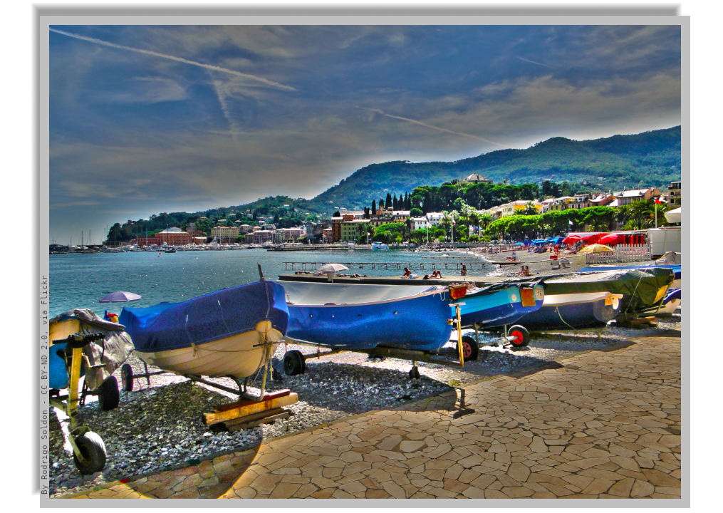 Some 'gozzi', the typical ligurian little boats, stranded on the beach, with panorama of the sea and the coastline in the background