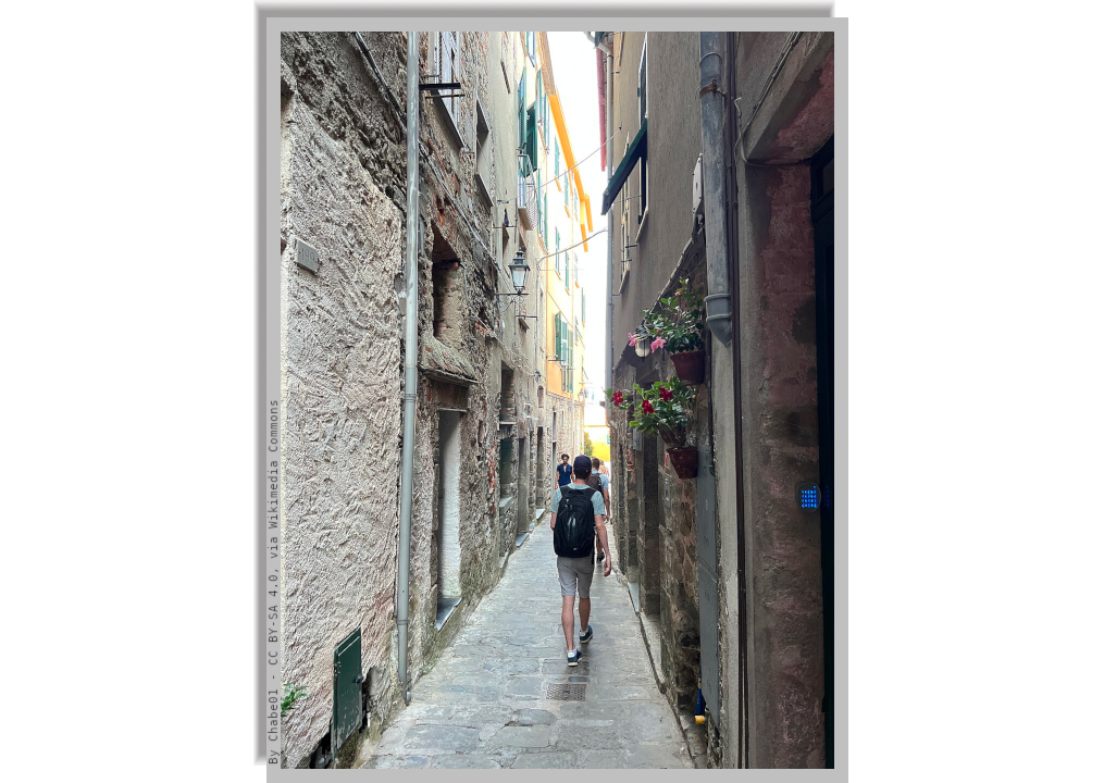 A tourist walks along a narrow alley betwen old stone houses