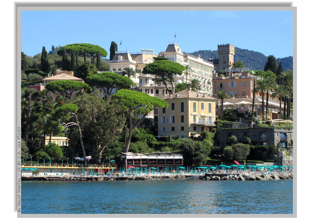 Sea coastline with deck chairs, tall maritime pine trees and large hotel complex