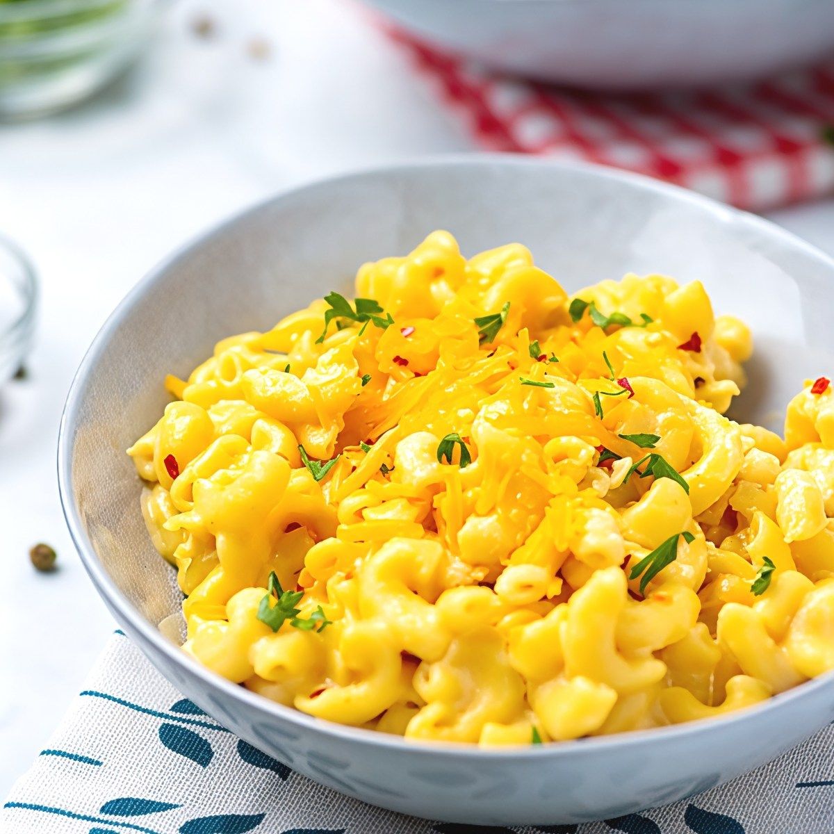 Bowl of delicious cheddar mac and cheese with fresh herbs and red pepper flakes garnish