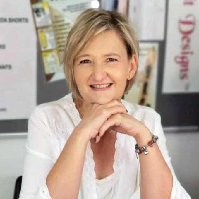 Picture of Elsabe a woman with fair skin and stylish short blond hair sitting at a desk with a white blouse 