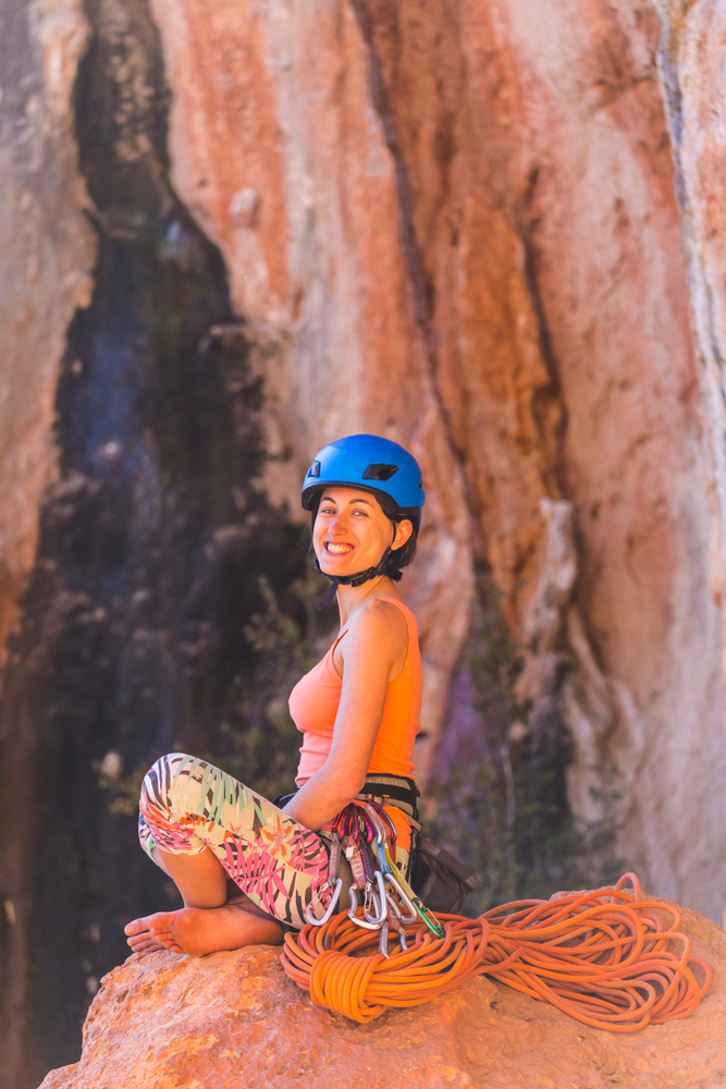 Female climbing instructor in colorful gear preparing at sandstone cliff