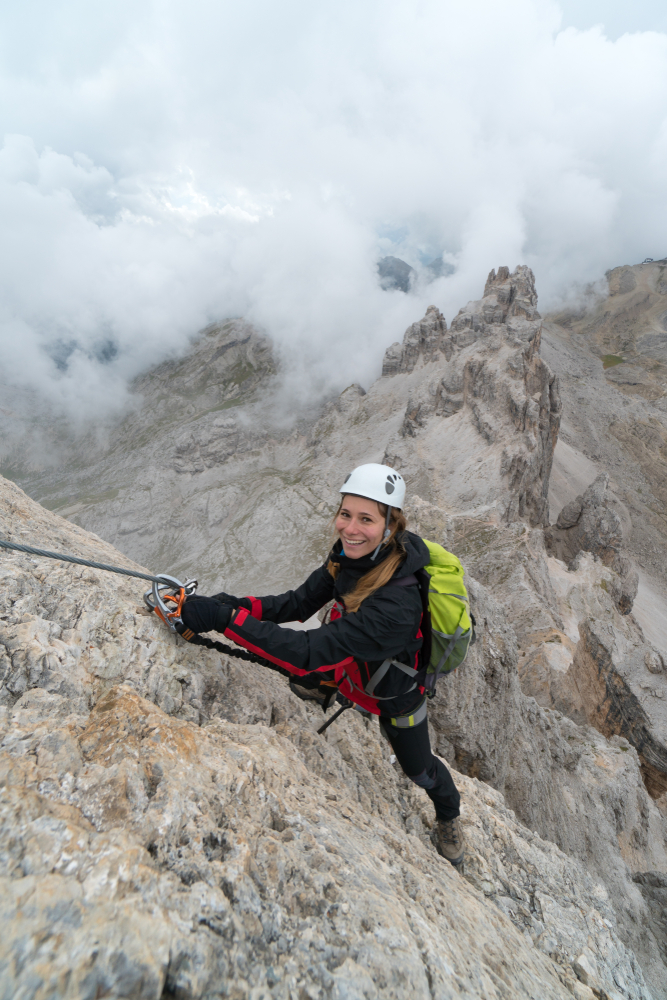 Female climber reaching the summit on a snowy cliff in Colorado with rope and helmet – alpine rock climbing