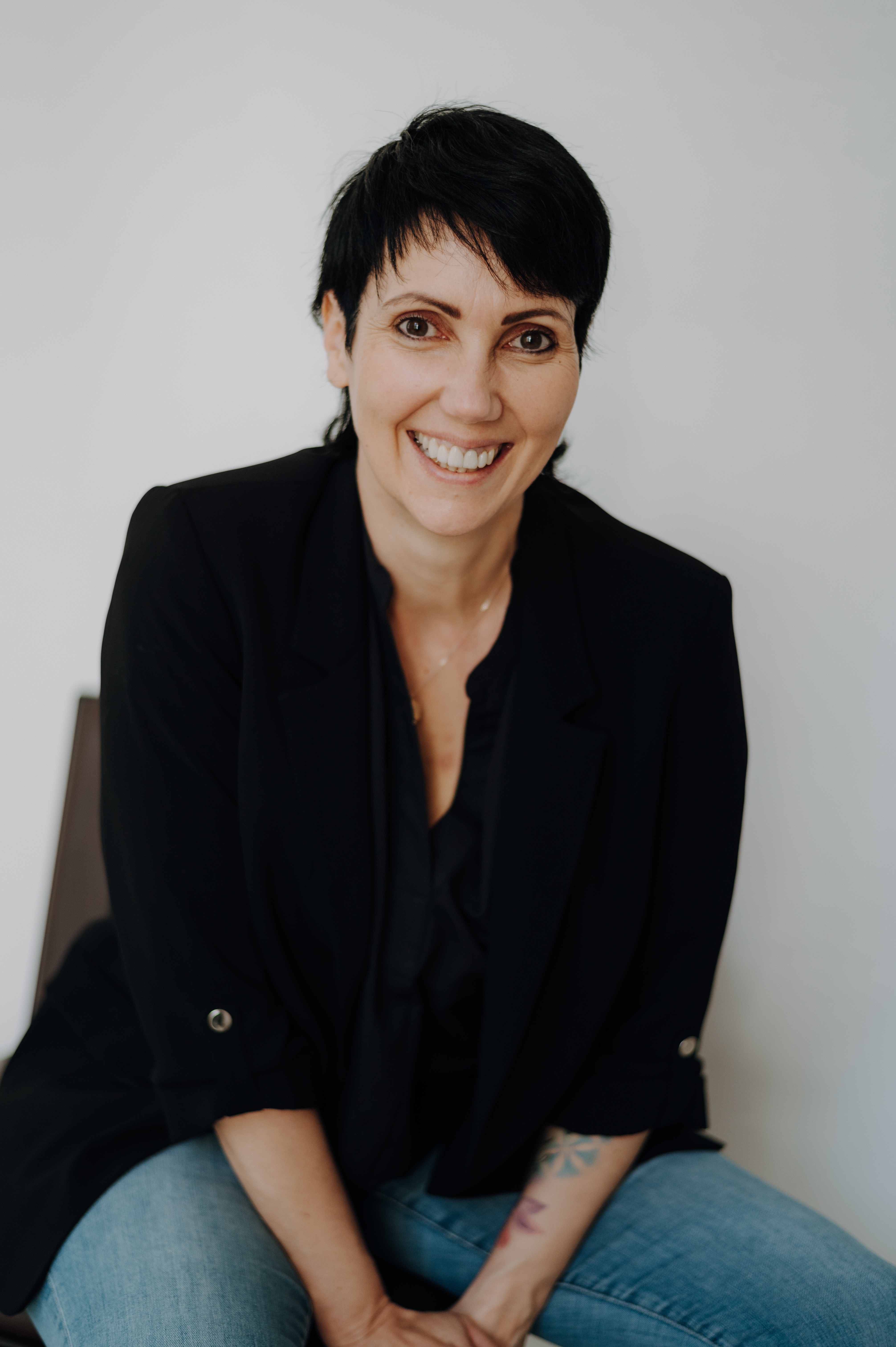 Esther Nott  steht an einer schönen Steinmauer und schaut freundlich in die Kamera