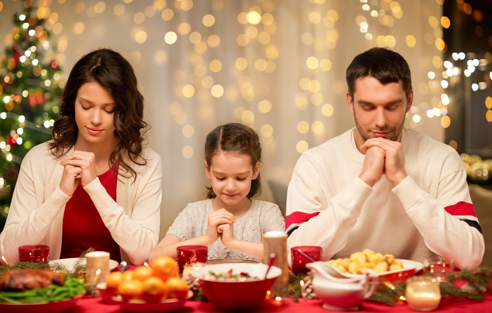 young girl saying grace at dinner