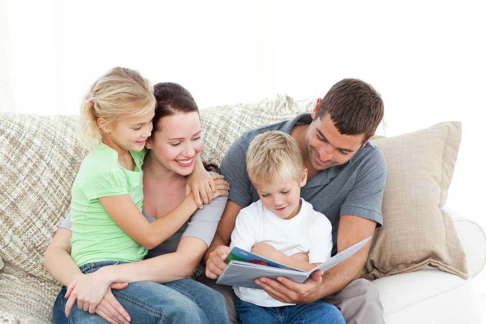 parents and kids reding a book on a couch