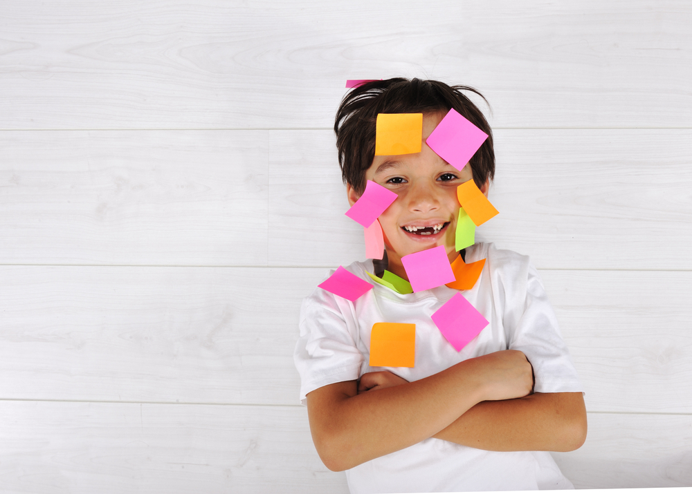smiling boy covered in colorful sticky notes