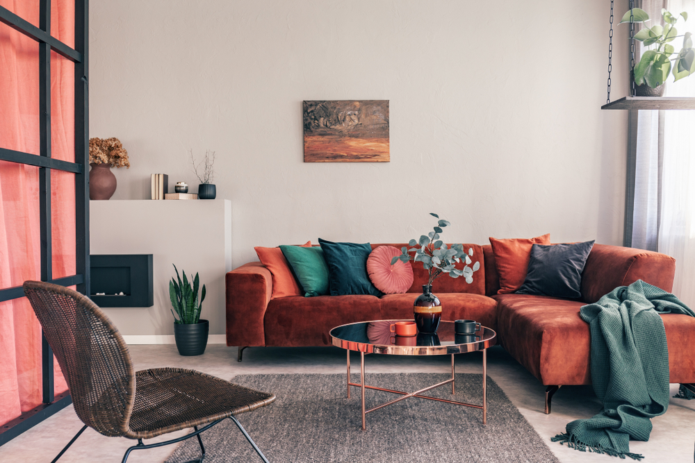 Coin salon avec un petit bout de sofa en tissu beige et une plante verte en pot, créant une ambiance naturelle et confortable dans la pièce.