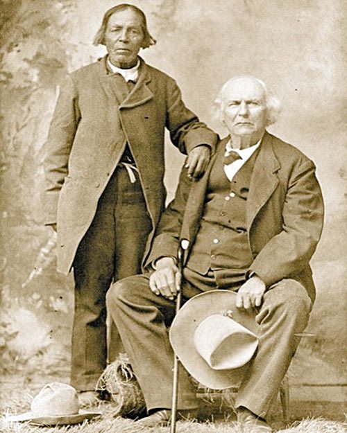 Ute Chief Conniach, also spelled Kaniache (standing left), with Uncle Dick Wootton (seated right).