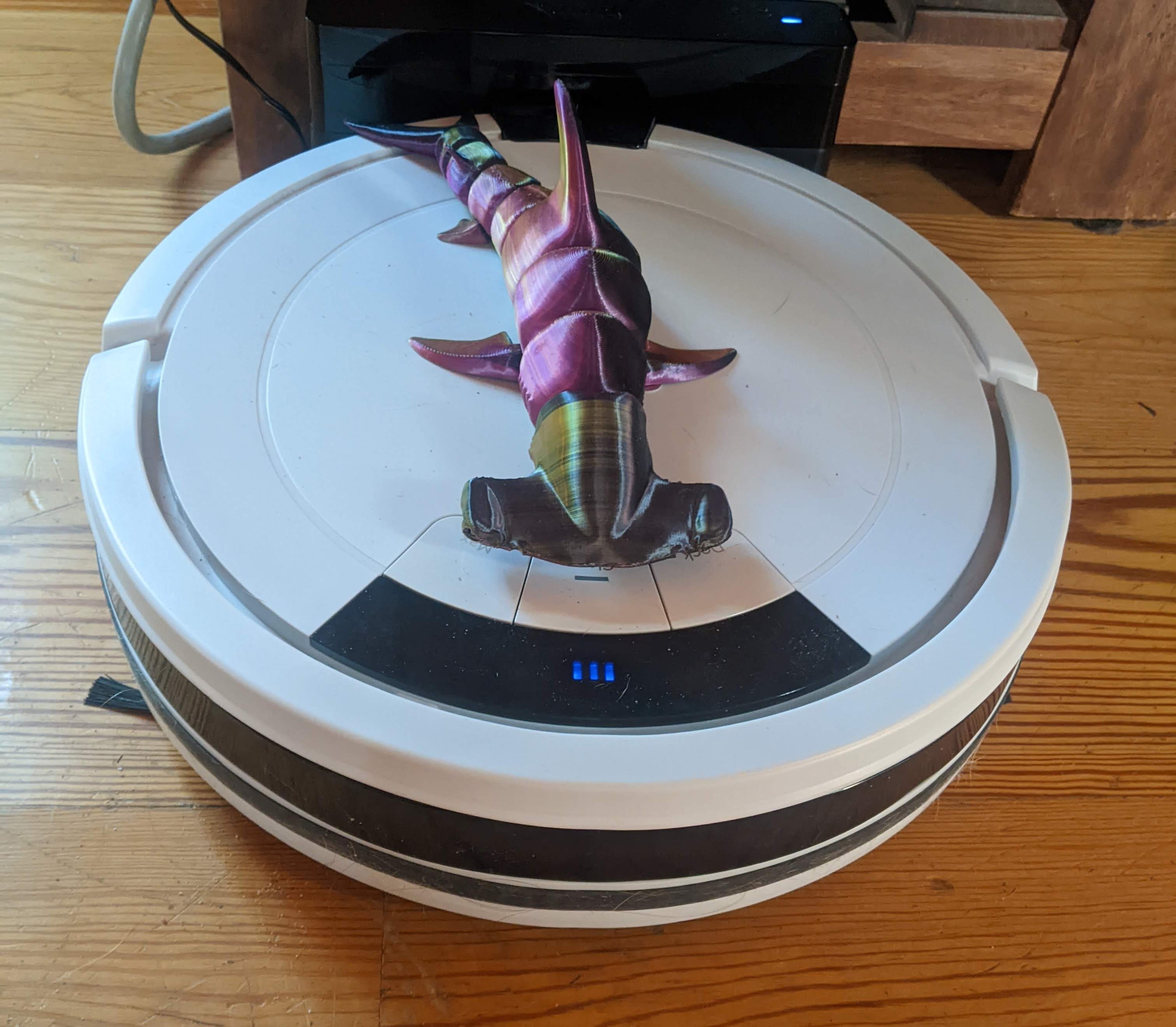 A picture of a 3D printed hammerhead shark hot-glued to the top of a Shark vacuum.