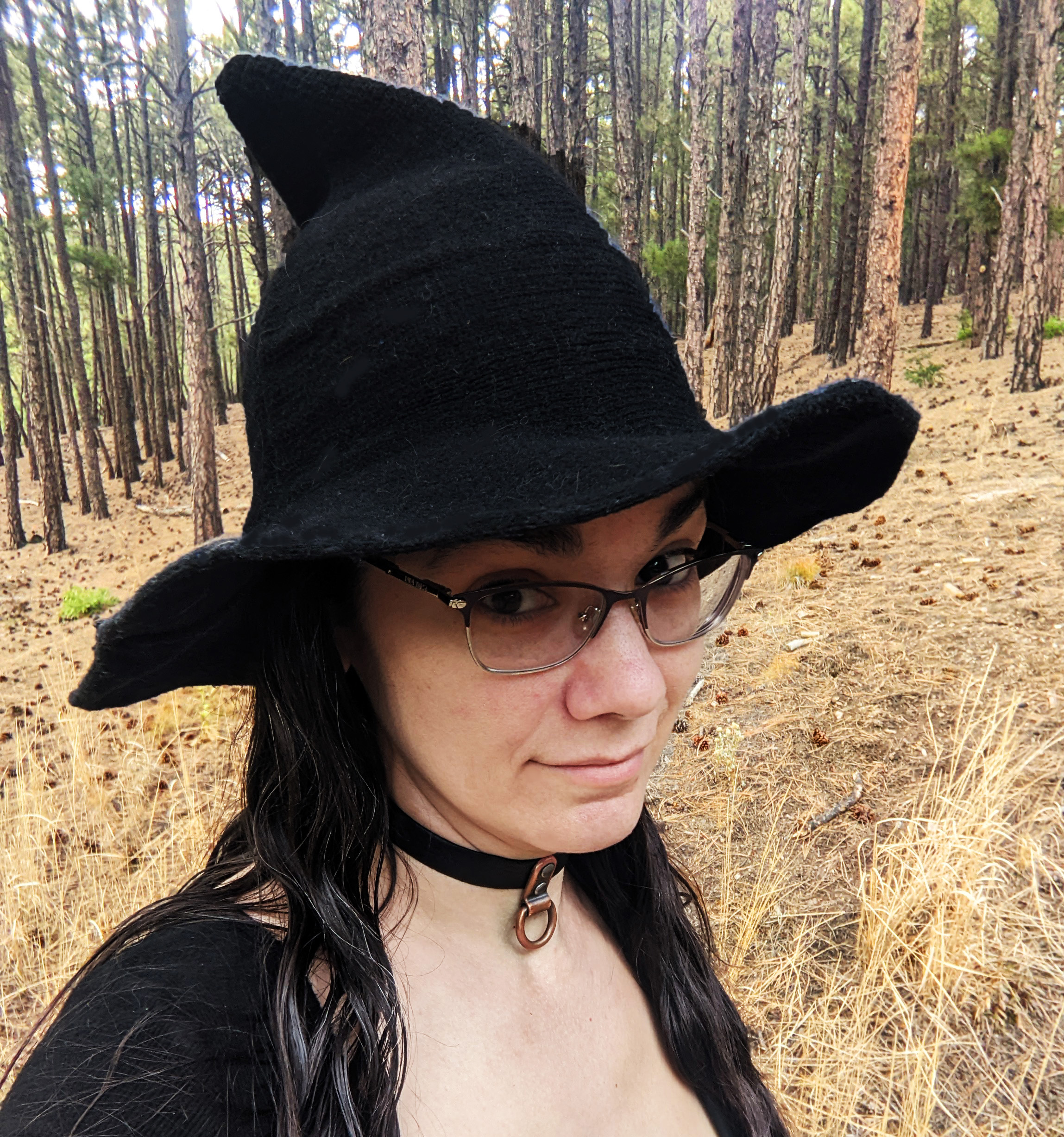 Jennifer Blackstream standing in the forest wearing a witch hat and making what she thinks is a mysterious face.