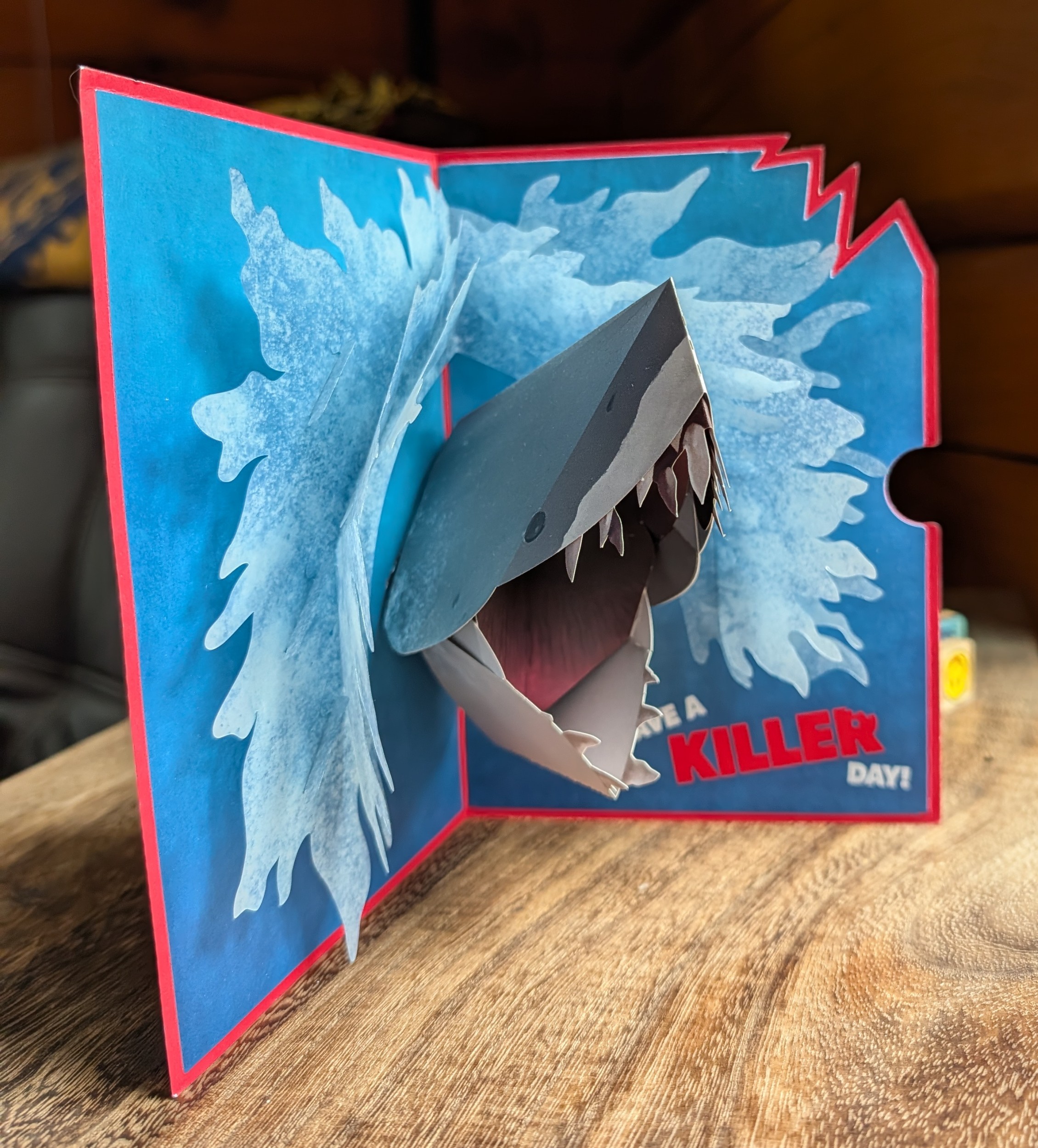 A pop up Jaws card with a shark erupting from the water and the text: “Have a Killer day!“
