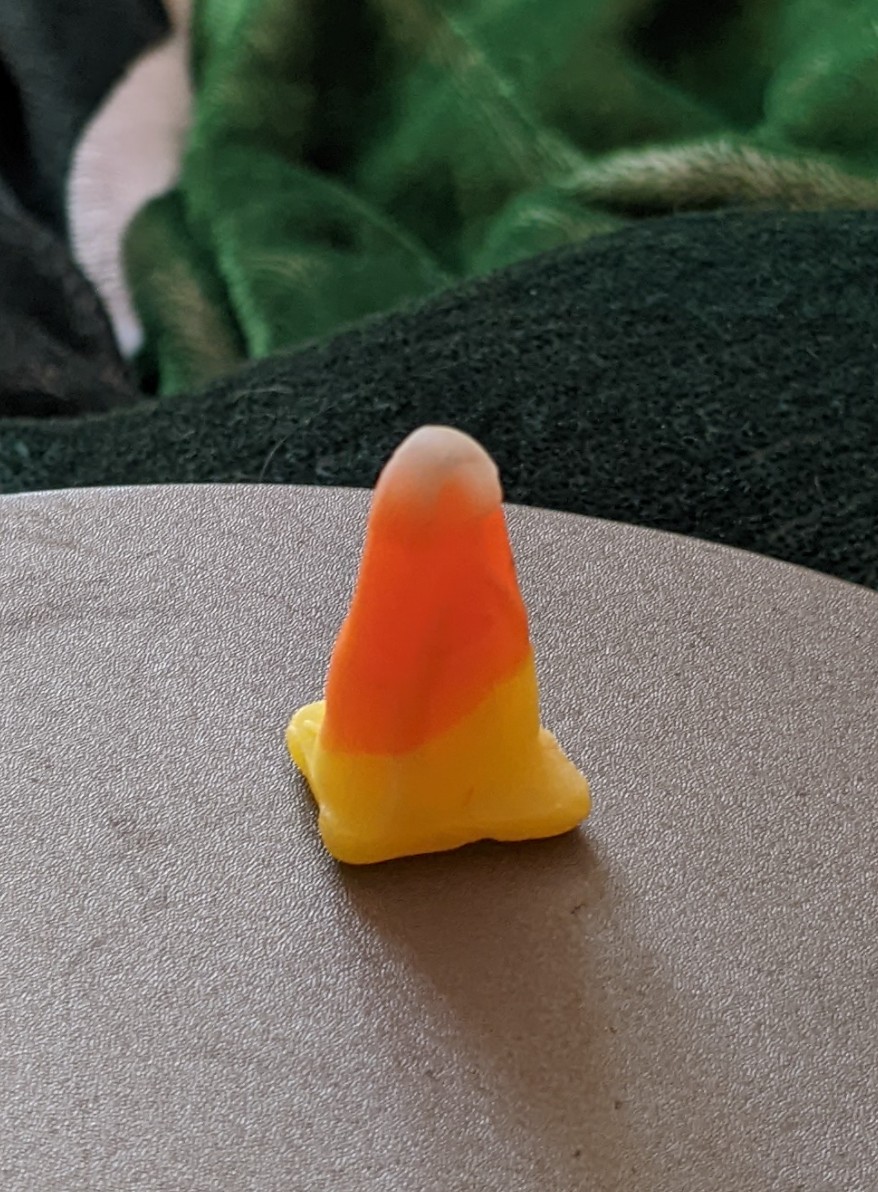 A picture of a candy corn standing up because the base got flattened into a square.