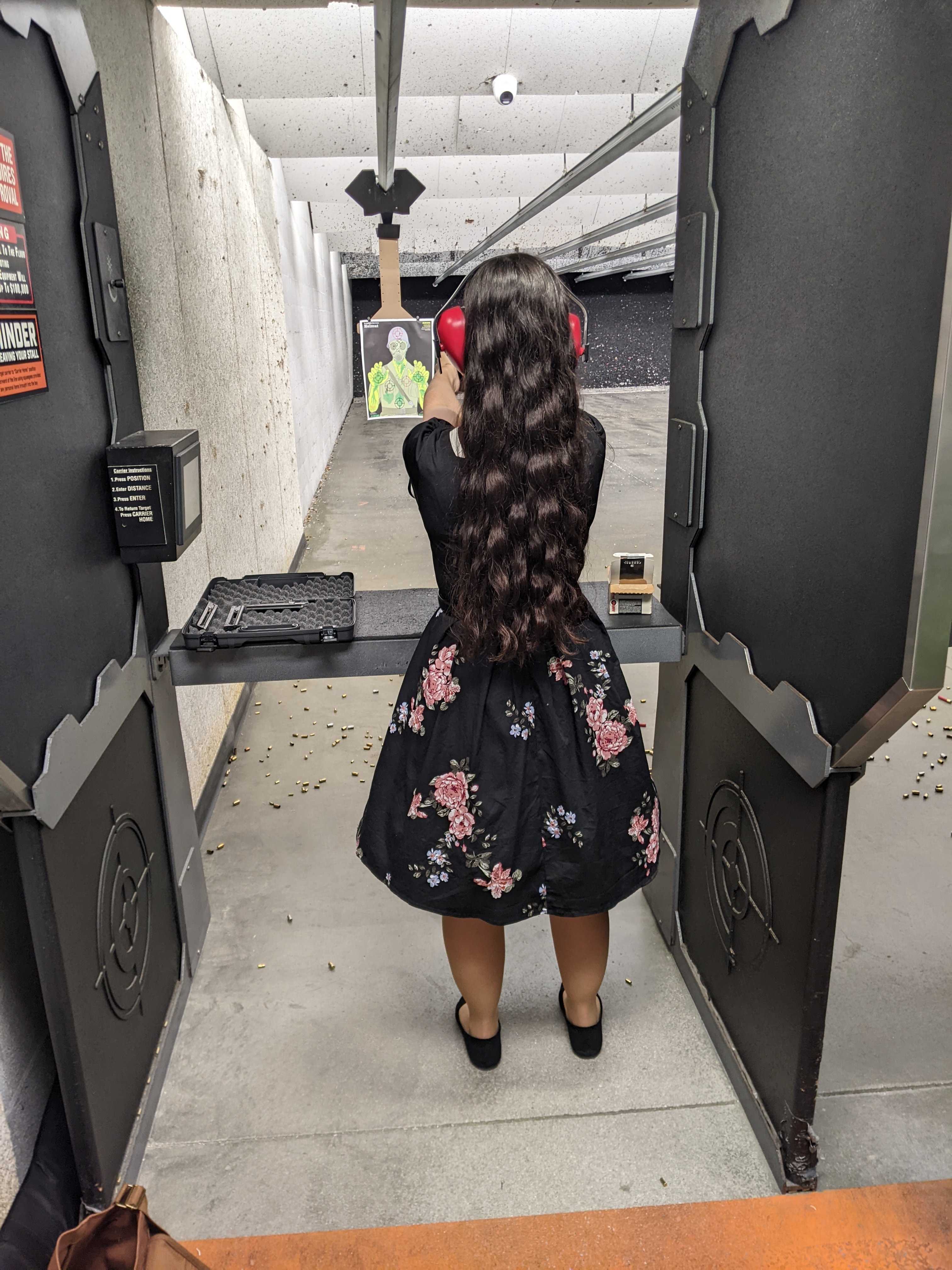 Picture of me at the shooting range aiming the gun and wearing a fifties style house dress including petticoat.