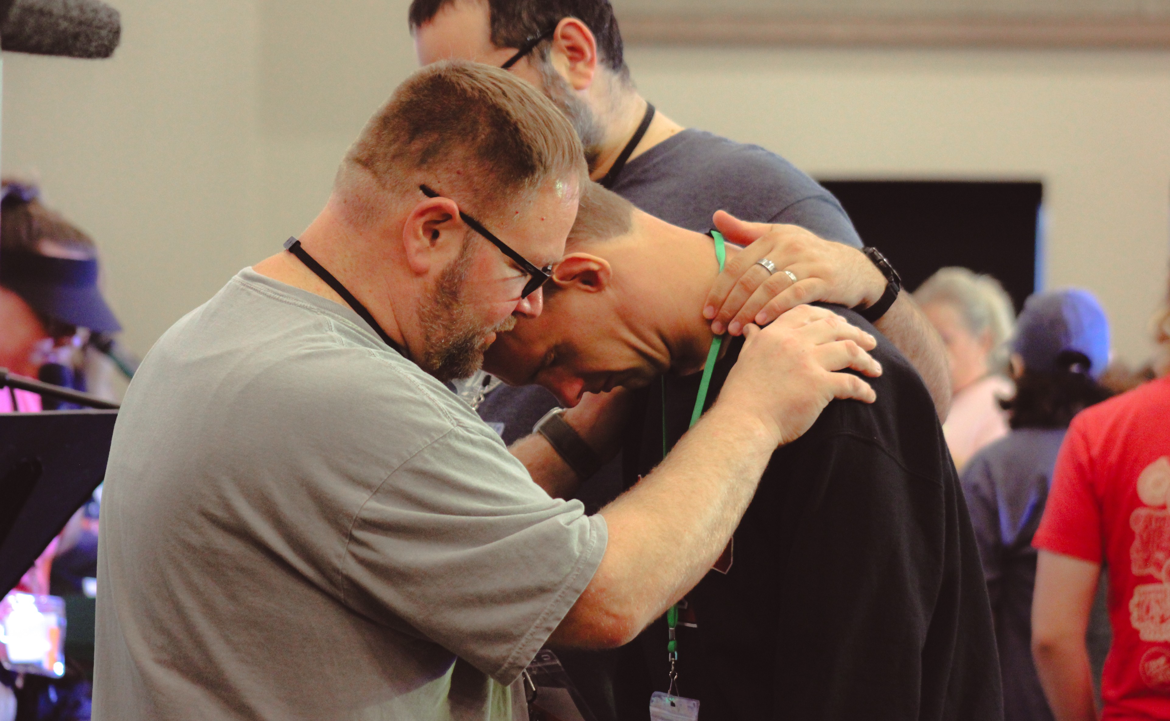 Two men praying with a third man