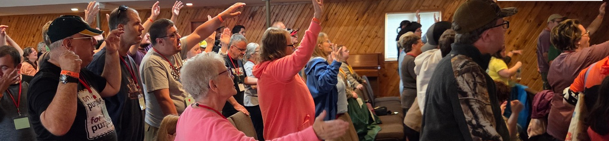 A room full of people standing and praising God