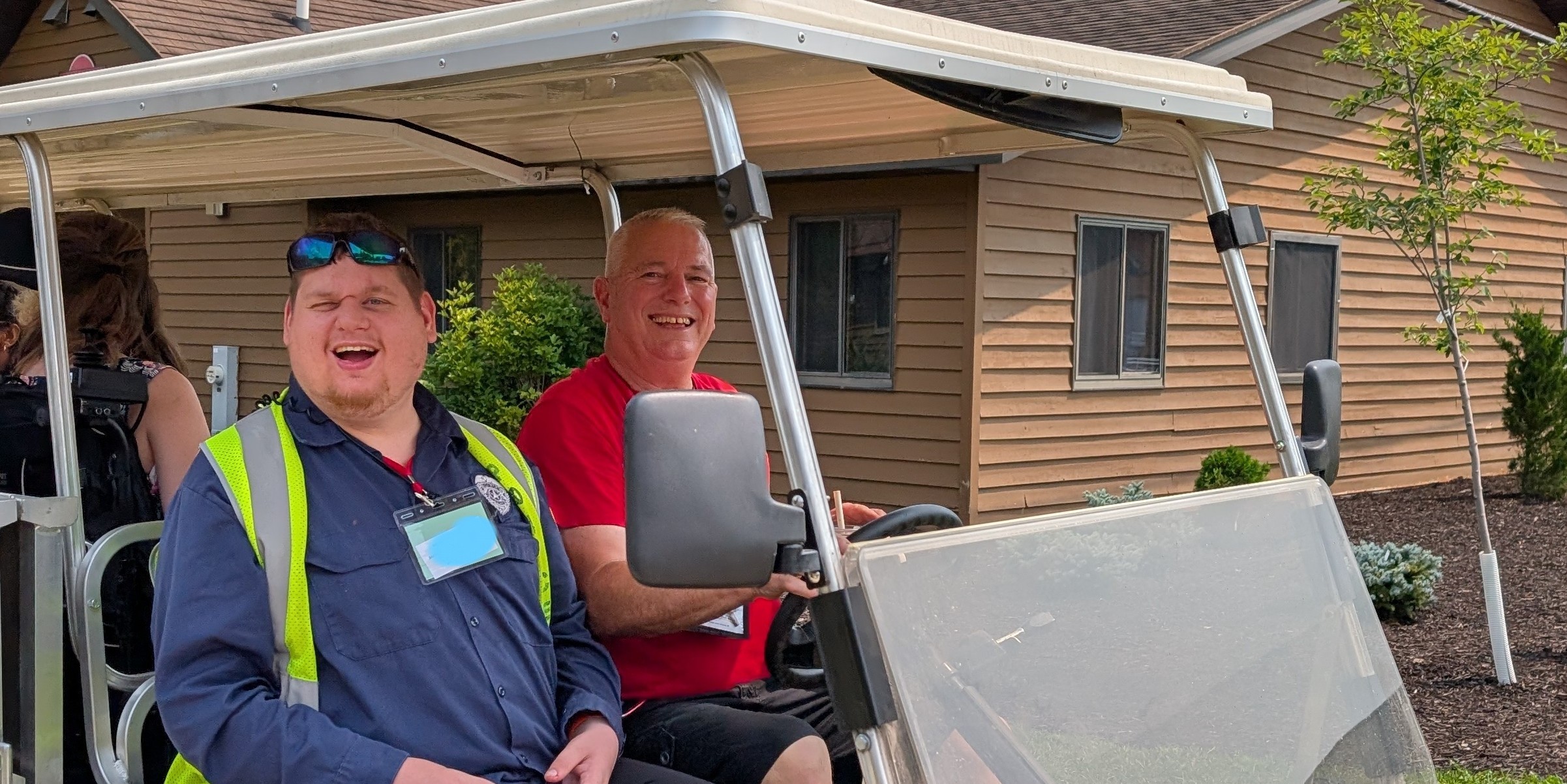 two men in a golf cart laughing in front of a cabin