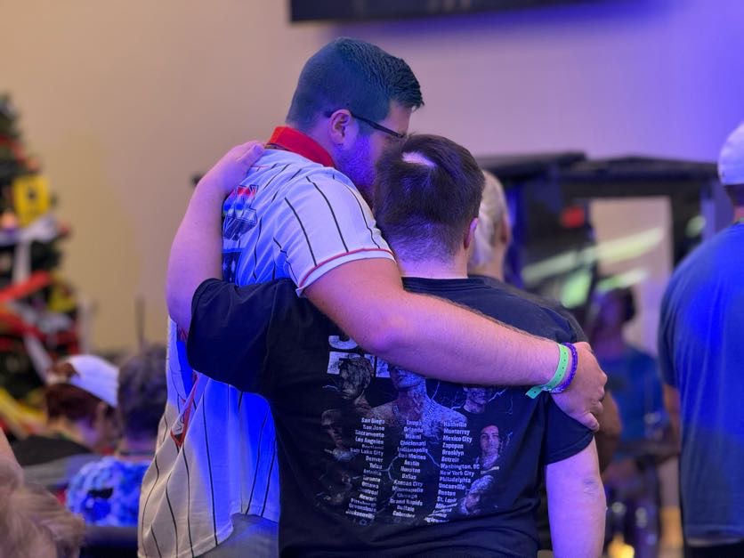 one person with his arm around another giving a side hug