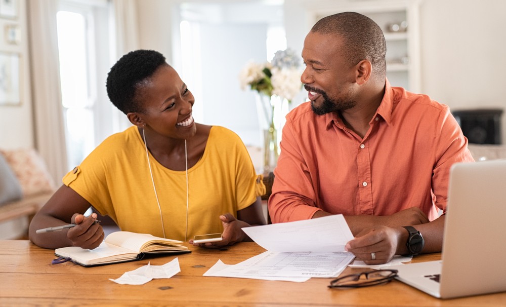 Man and woman sitting at a desk working on taxes smiling