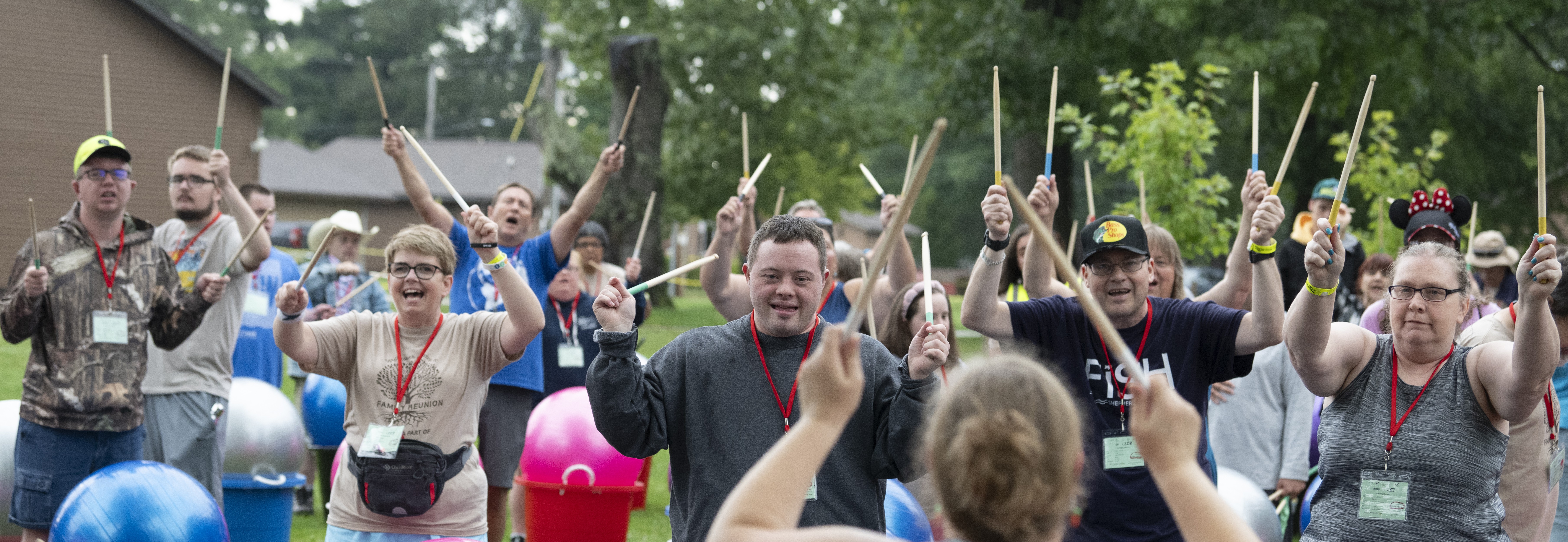 group of people waving drumsticks in the air smiling and having a good time