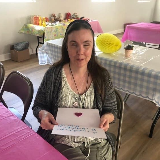 Smiling woman who is blind receiving a card in braille