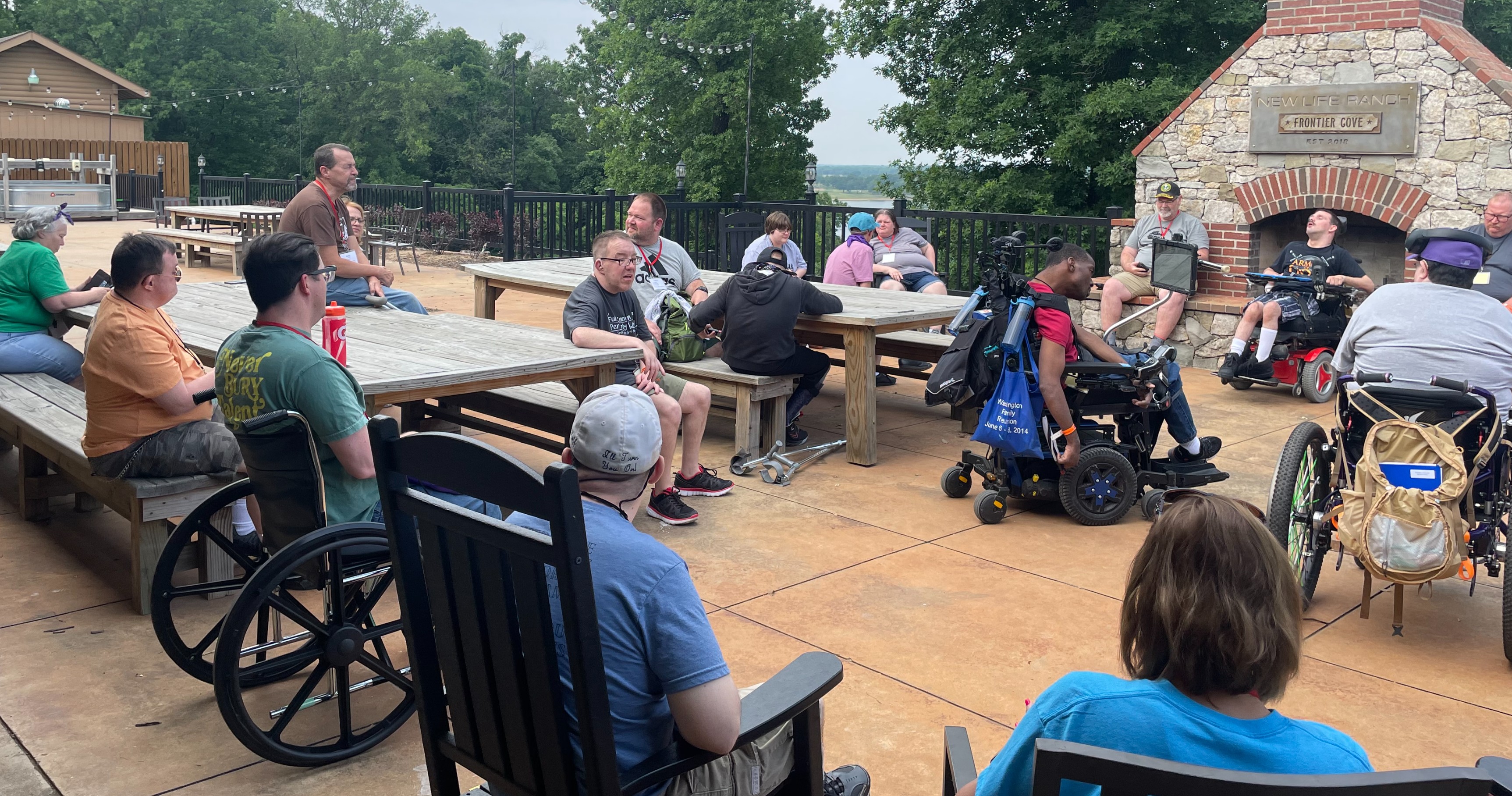 People sitting out on a patio meeting together some of them using wheelchairs