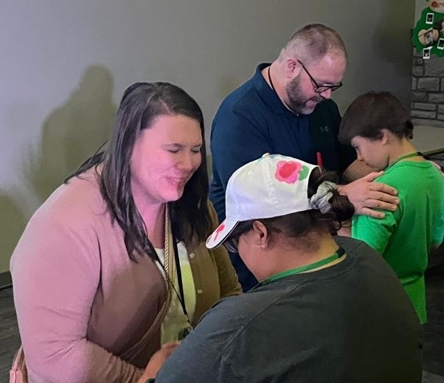 Duane and Tracie praying with two people